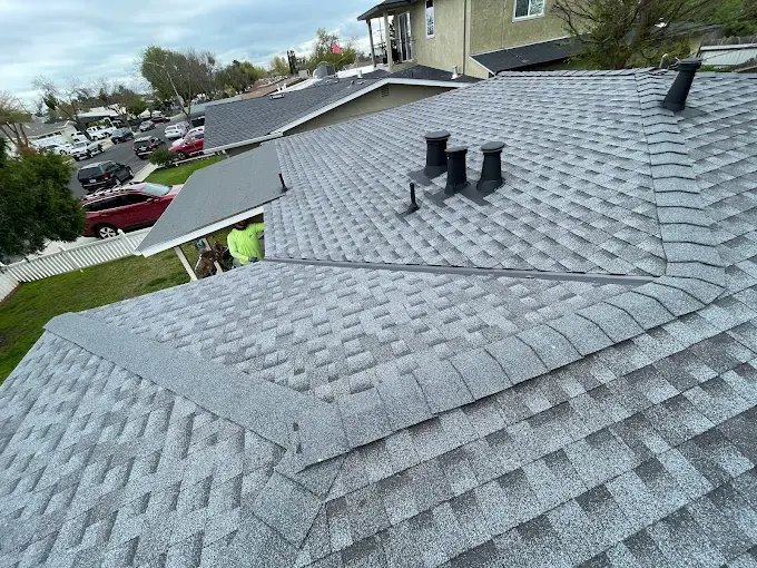 Close-up of a well-maintained asphalt shingle roof in Modesto California with lush landscaping and sunny sky