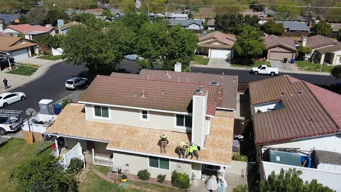 Close-up of a newly installed roof vent on a Modesto California home with neat shingles, green trees, and cityscape background