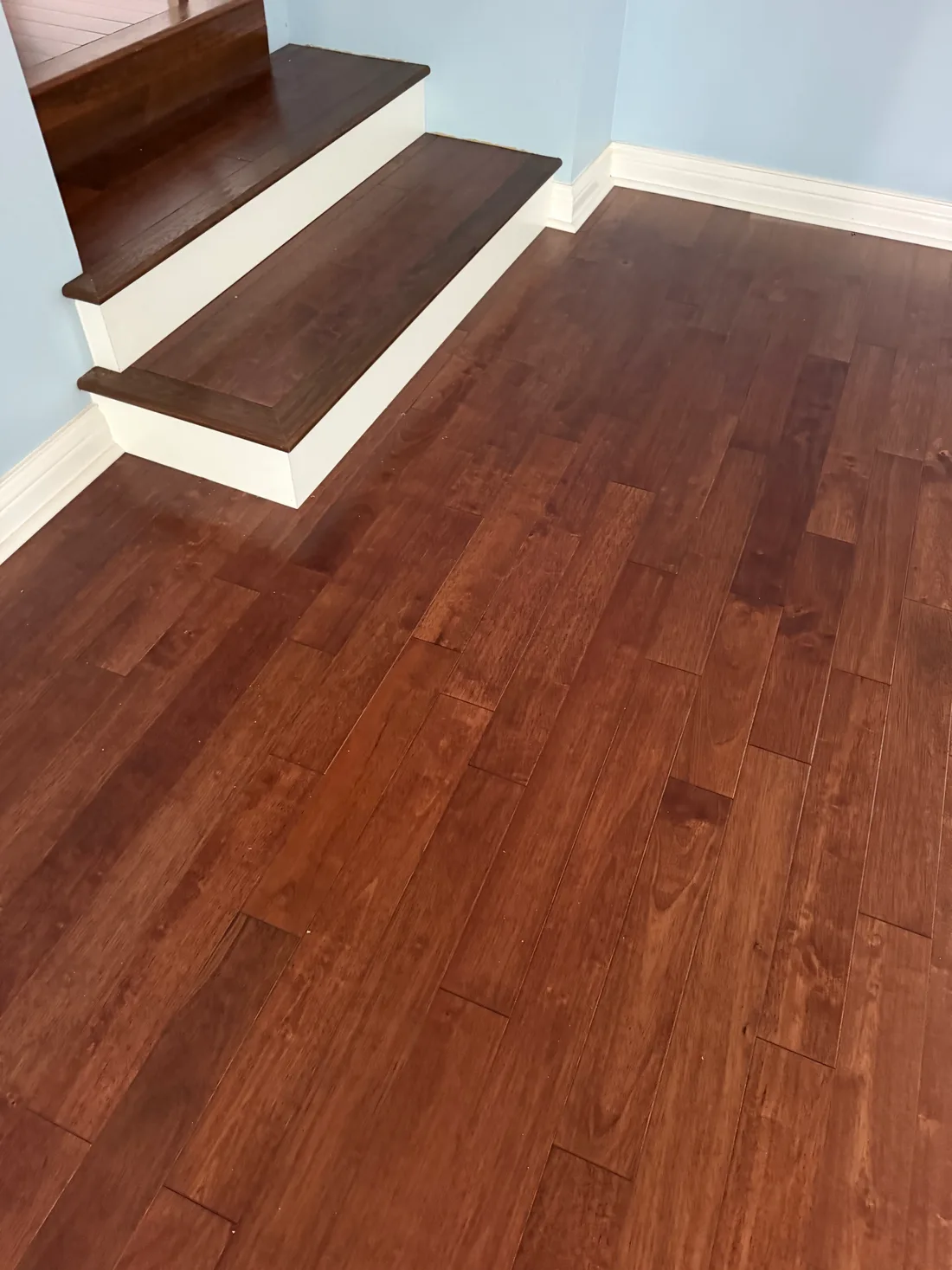 Spacious room with polished hardwood flooring, bright light, neutral walls, and a cozy area rug in Darien, IL.