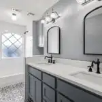 Completed modern bathroom vanity in Austin with granite countertop black faucet vessel sink gray textured tiles hardwood floor