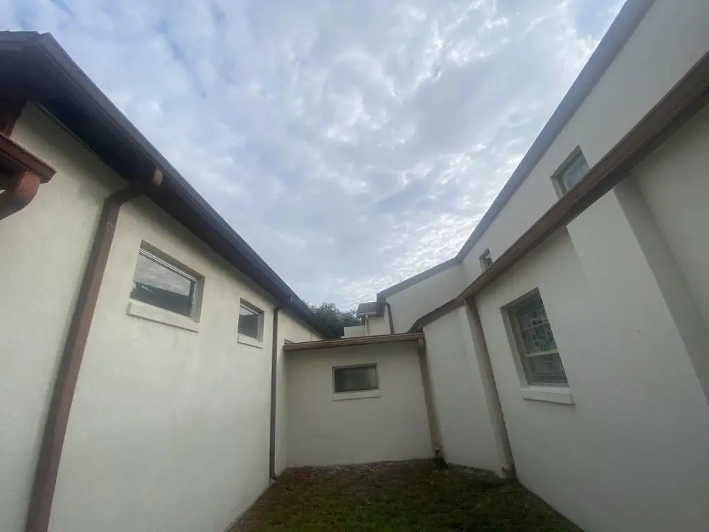 Stucco repair in New Smyrna Beach, FL, features smooth sandy beige finish with lush landscaping and palm trees.