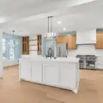 Modern kitchen with a marble island, stainless steel appliances, warm wood cabinets, large windows showing Texas landscape
