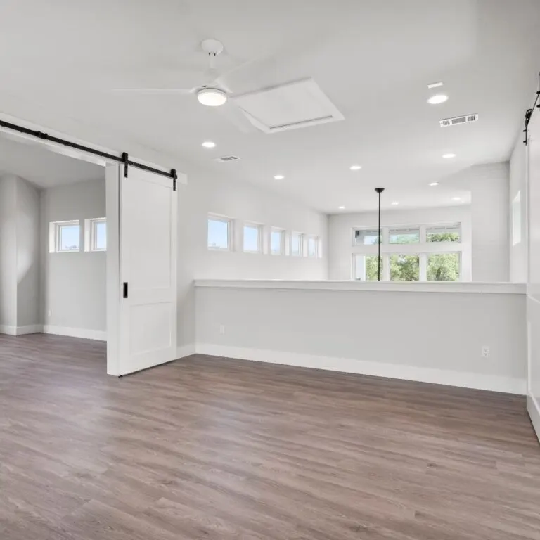 Recently remodeled kitchen in Austin, featuring neutral cabinetry, quartz island, stainless appliances, and hardwood floors.