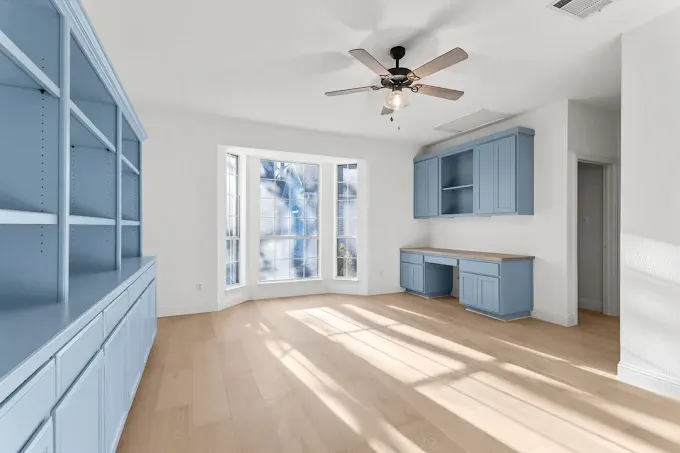Completed modern ADU in Austin TX showing sleek design, large windows, landscaped yard, mature trees, and blue sky