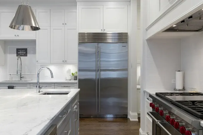 Renovated Austin kitchen with navy cabinetry stainless steel appliances quartz island stone backsplash hardwood floors and natural light