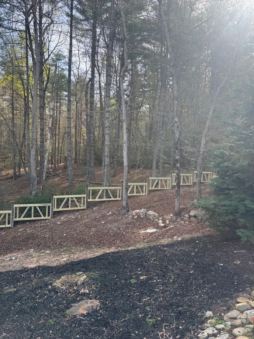 Completed wooden fence installation in Ellijay GA with rich natural finish, vibrant wildflowers, and rolling hills.