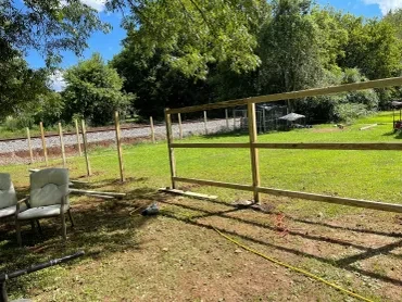 Elegant wooden fence installation in Cohutta GA surrounded by green grass and wildflowers under a clear blue sky.