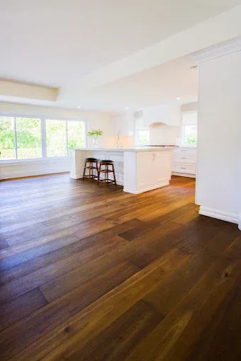 Hardwood floor baseboard installation in a modern living room with polished floors and coastal decor in Naples FL.