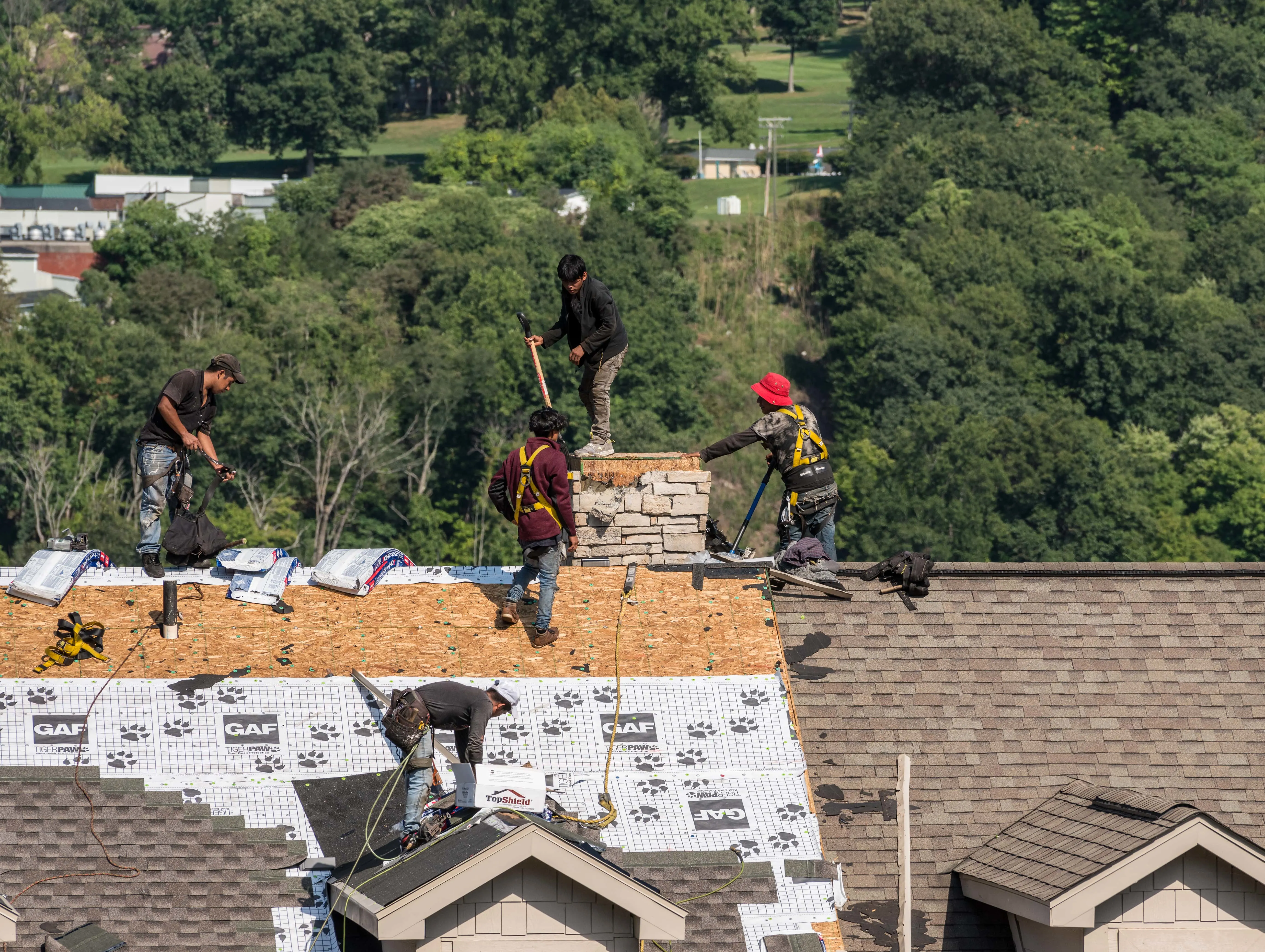 Freshly inspected modern roof with detailed shingles, clean alignment, lush lawn, suburban neighborhood, bright sky