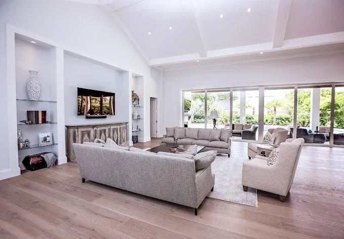 Spacious living room in Estero FL with polished oak and maple wood flooring, natural light, and elegant decor.
