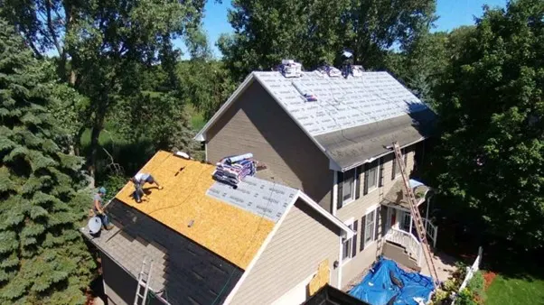 Well-maintained residential house in Modesto CA with a freshly repaired roof featuring neat shingles under bright sunlight surrounded by lush greenery