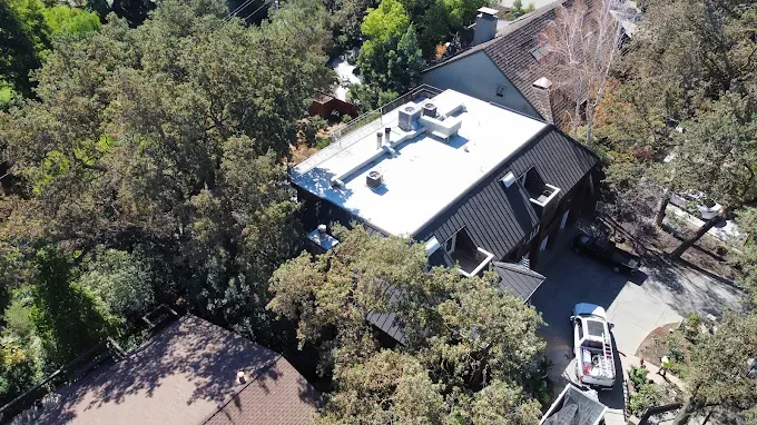 Well-maintained residential roof in Modesto with detailed shingles, clean gutters, lush neighborhood and clear blue sky