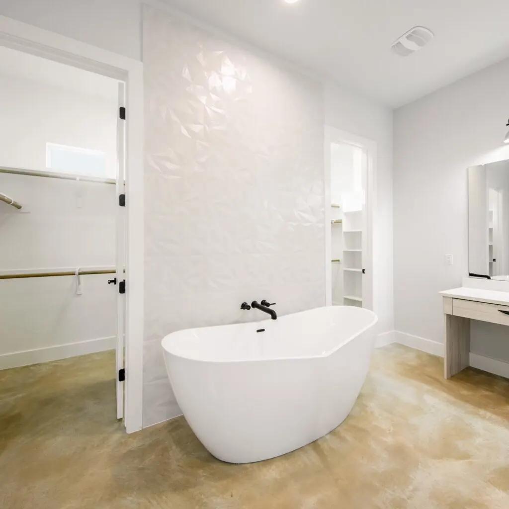 Modern upscale bathroom in Austin with white acrylic freestanding bathtub, chrome fixtures, natural light, lush Texas plants