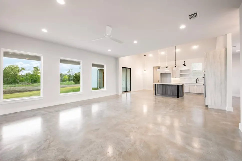 Modern kitchen remodel in Mueller TX featuring white cabinetry, quartz countertops, and dark hardwood flooring with garden view.