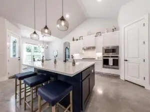 Finished modern ceramic kitchen backsplash with earthy tones in a herringbone pattern, white quartz counter and sunlight in Austin