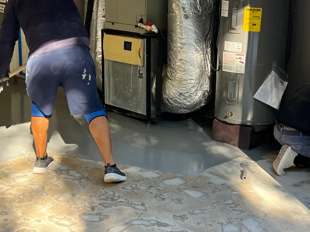 Glossy Polyaspartic floor coating in a bright Jacksonville garage, featuring deep grays and white-blue flecks, organized tools.