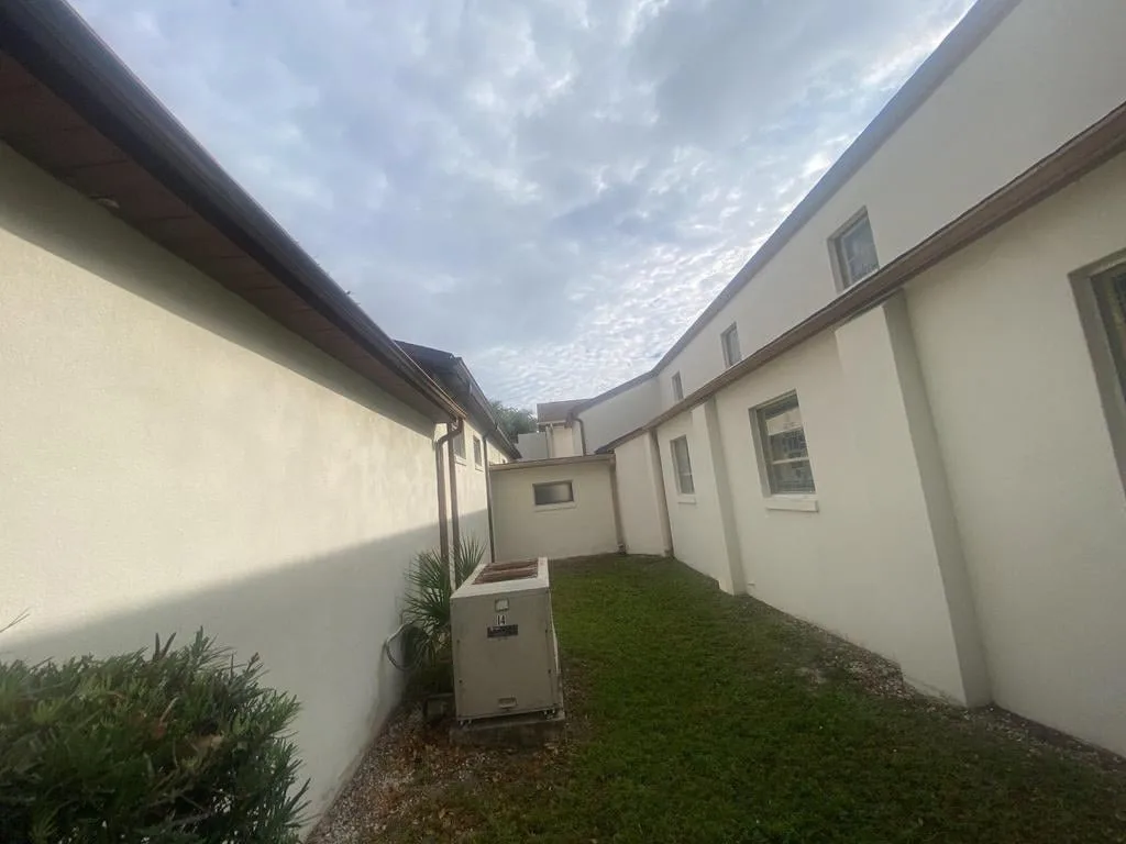 Stucco repair in New Smyrna Beach FL showcasing flawless texture, coastal colors, palm trees, and sunny skies.