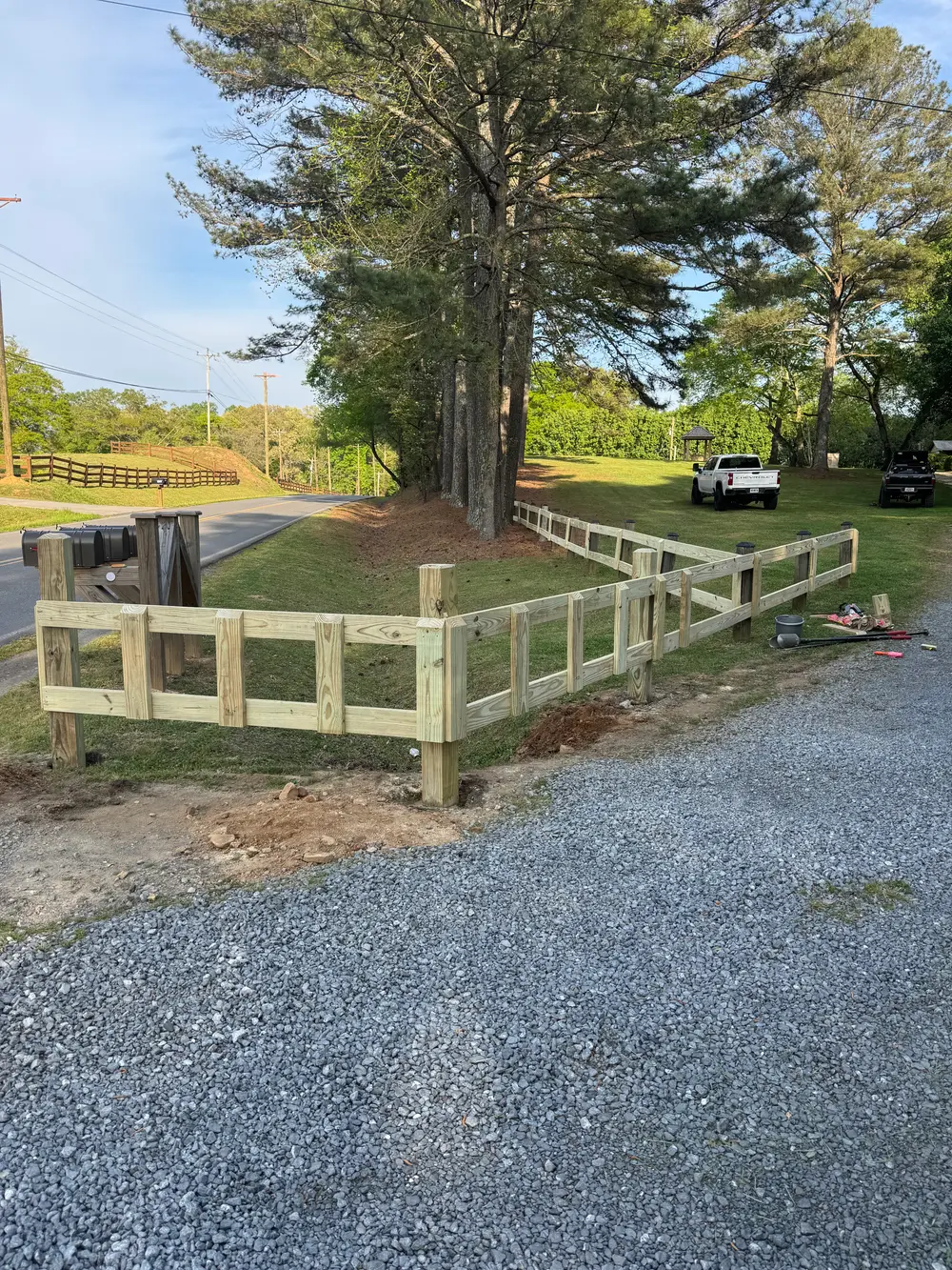 Wooden fence in lush greenery of Cohutta GA with rolling hills, blue sky, and peaceful rural scenery.