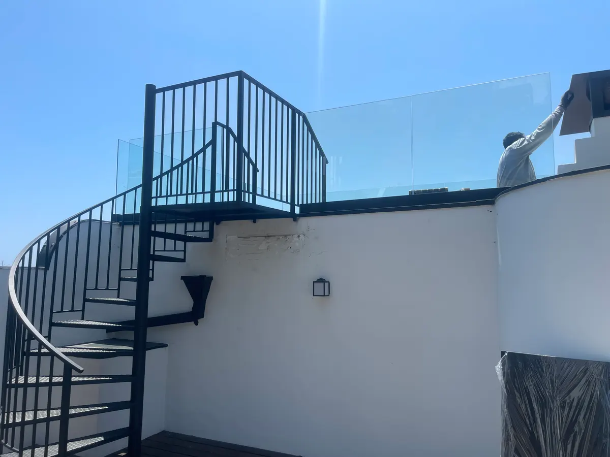 Custom wrought iron gate installation in Los Angeles with lush landscaping and clear blue sky backdrop.