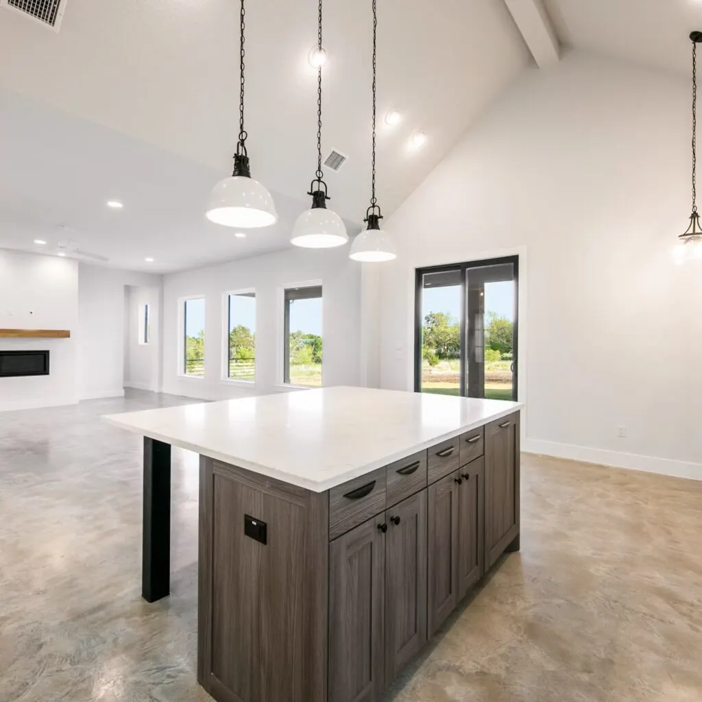 Modern kitchen remodel in Spicewood TX features marble island, stainless appliances, and elegant cabinetry with natural light.