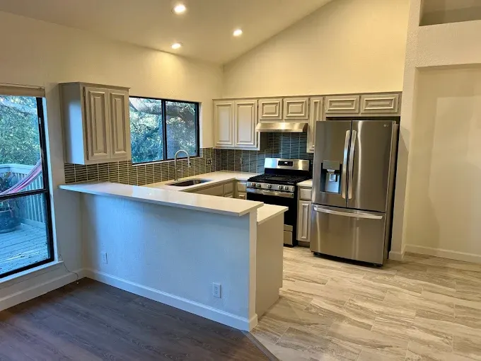Stunning kitchen remodel in Lost Creek TX with quartz countertops, stainless steel appliances, custom cabinetry, and elegant lighting.