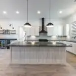 Modern kitchen remodel in Steiner Ranch TX with marble countertops, sleek cabinets, and lush green views through windows.