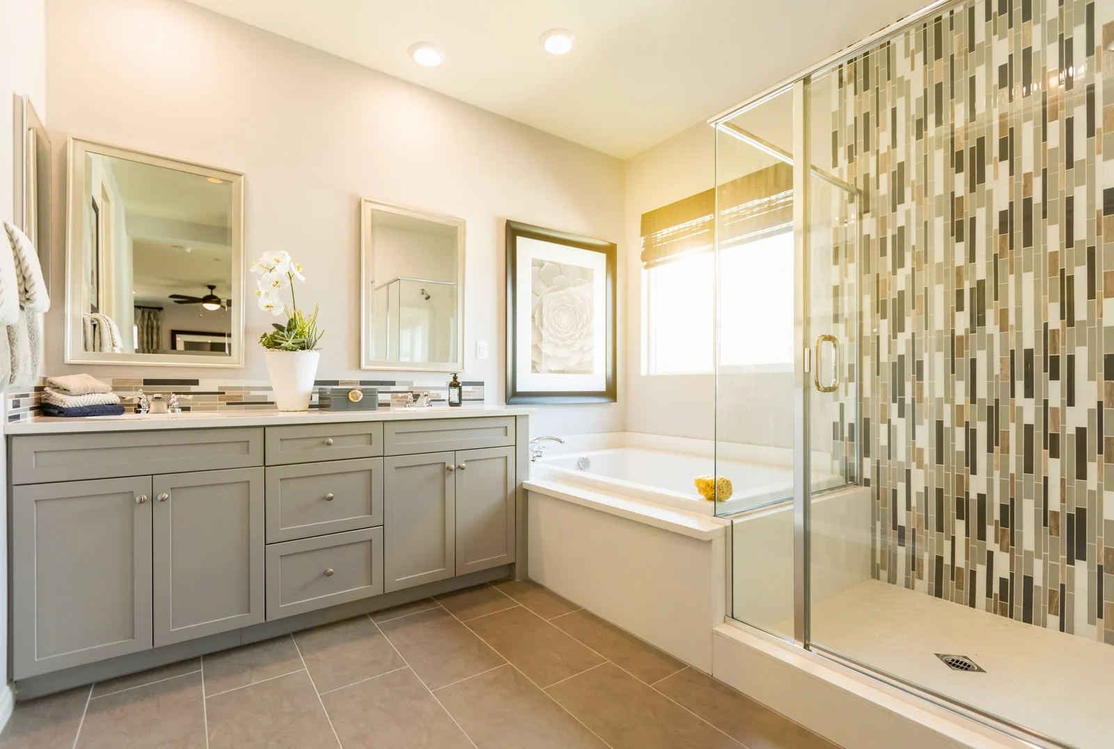 Beautiful modern Fort Worth bathroom remodel featuring white marble countertops, a soaking tub, glass shower, and elegant fixtures