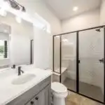 Modern bathroom vanity in Austin with marble countertop, natural wood cabinet, neutral tiles, and sleek hardware