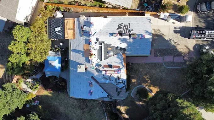 Finished dark asphalt shingle roof on Modern home in Modesto with lush landscaping and California trees under clear sky