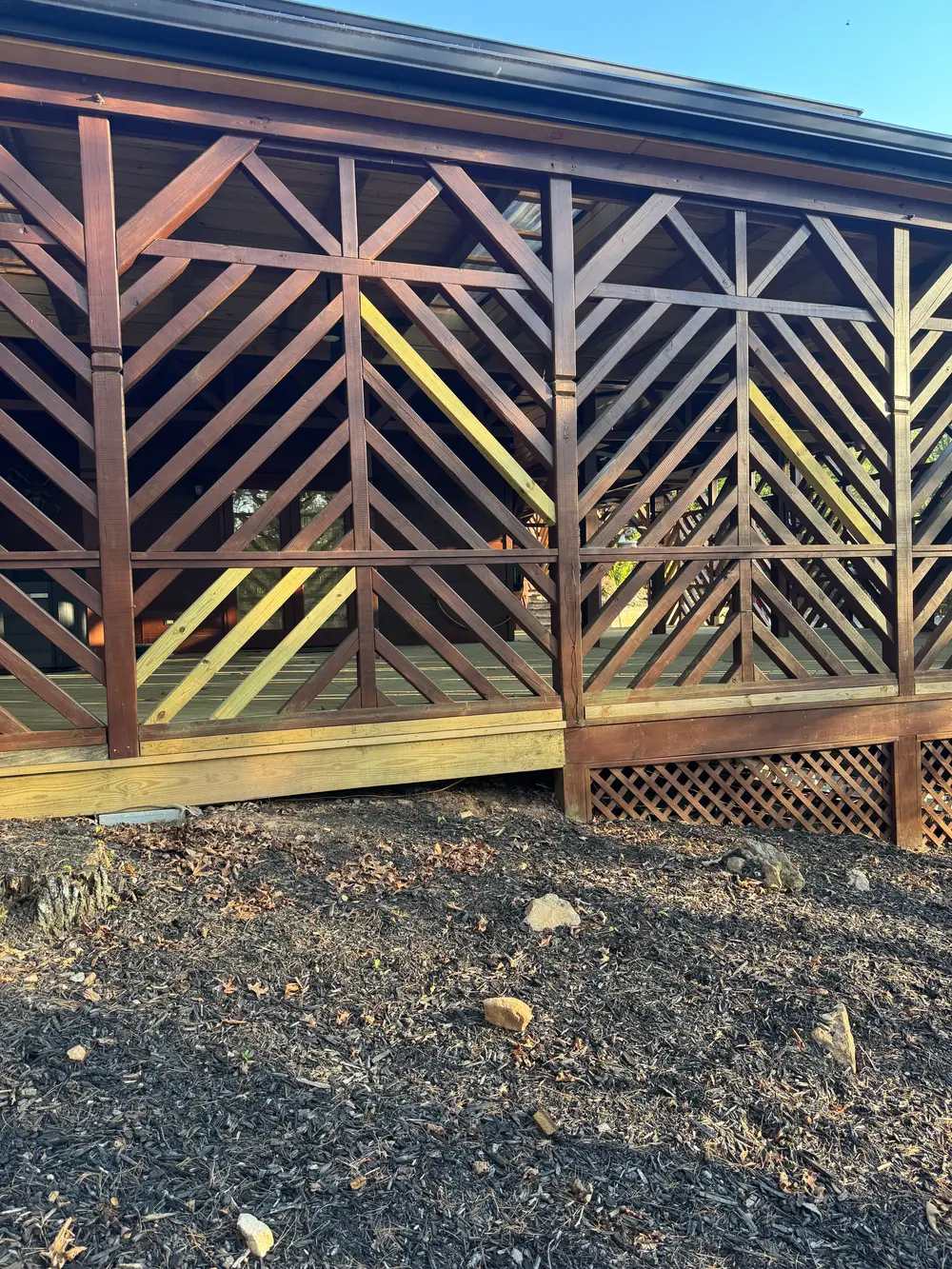 Beautiful wooden gate repair in Cohutta GA surrounded by vibrant flowers and manicured yard under a clear blue sky.