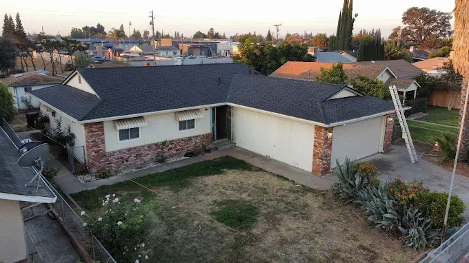 Pristine clean gutter system on a sunny suburban house in Modesto California with lush landscaping and clear blue sky