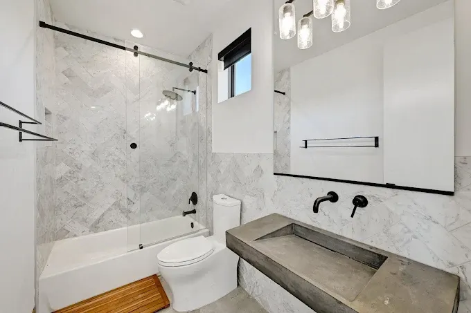 Modern kitchen remodel in Buda TX features elegant marble countertops, high-end appliances, and cozy dining area.