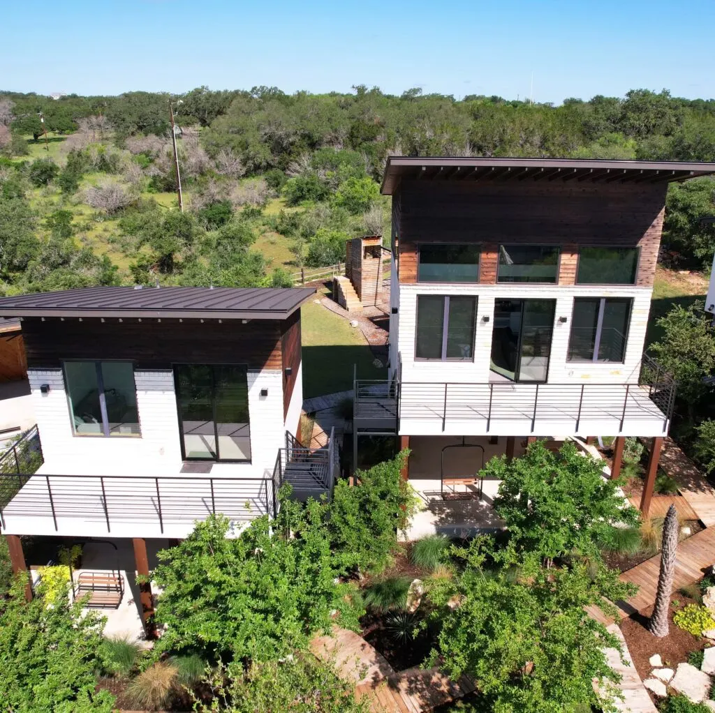 Covered patio in Austin TX with a wooden pergola, stylish furniture, lush garden, blue sky, and ambient lighting