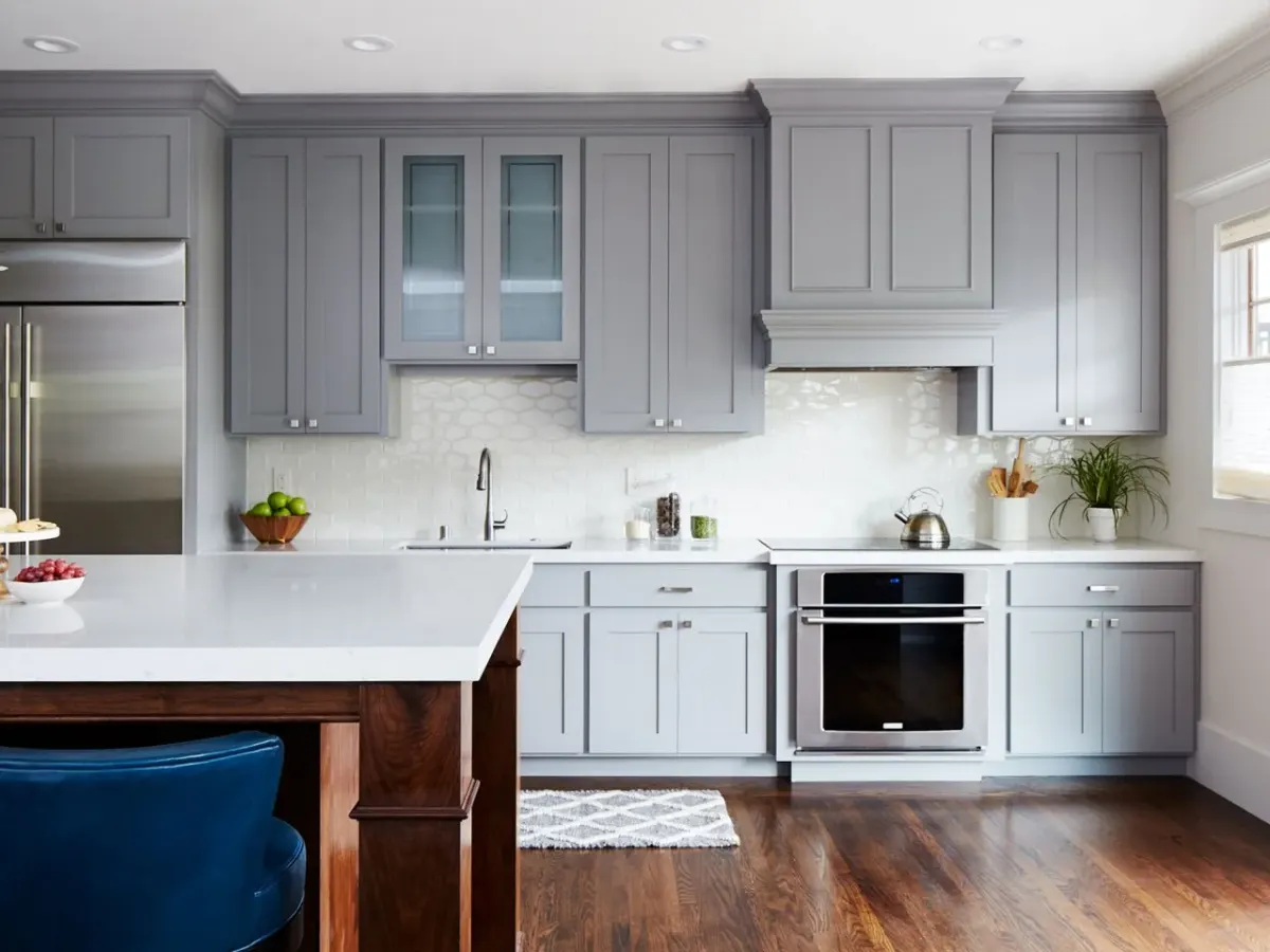Stylish kitchen featuring gray cabinetry, white countertops, stainless steel appliances, an island, and wood floors.