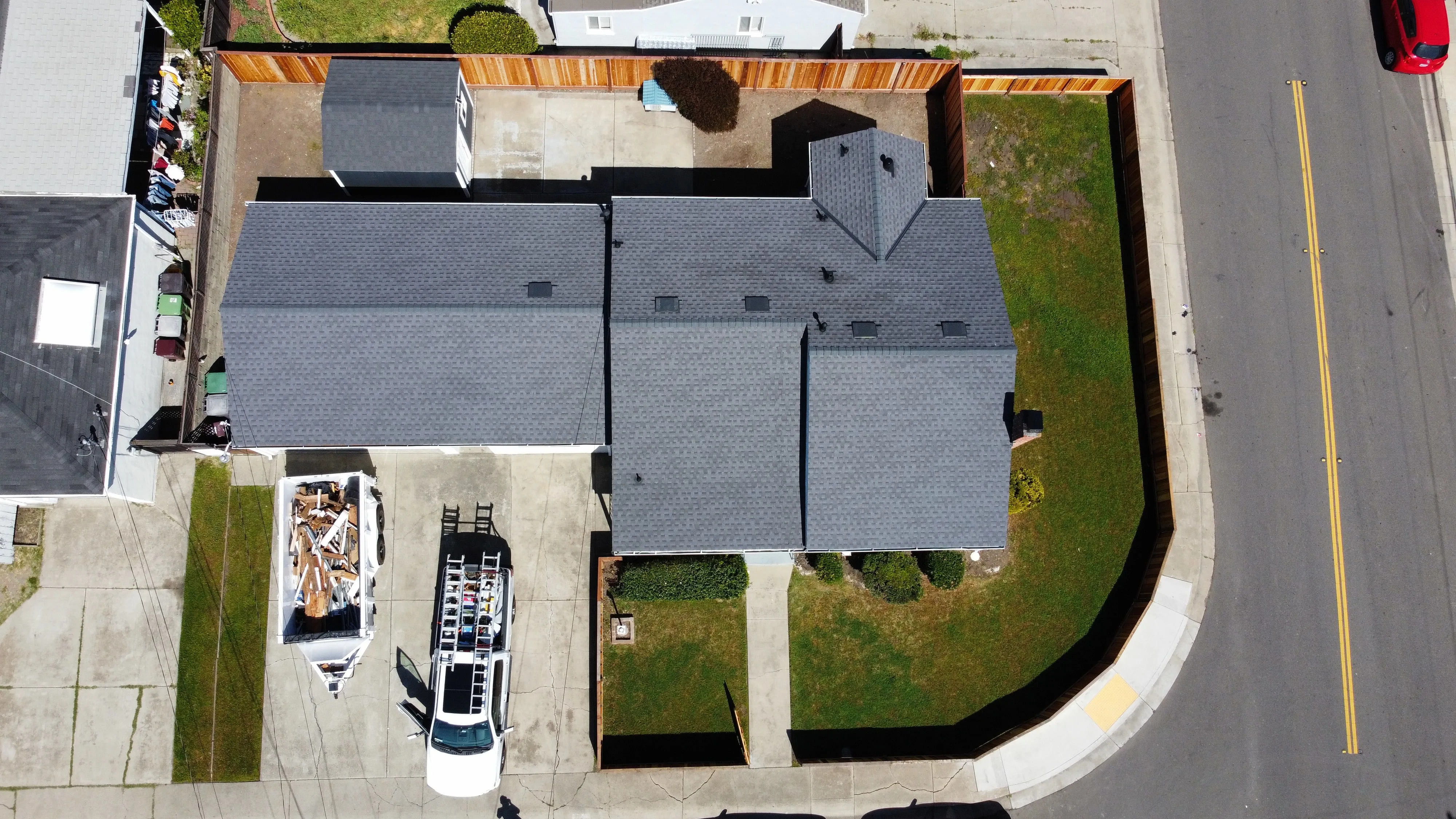 Freshly completed asphalt shingle roof on a modern home in Modesto CA, surrounded by vibrant landscaping and clear skies.