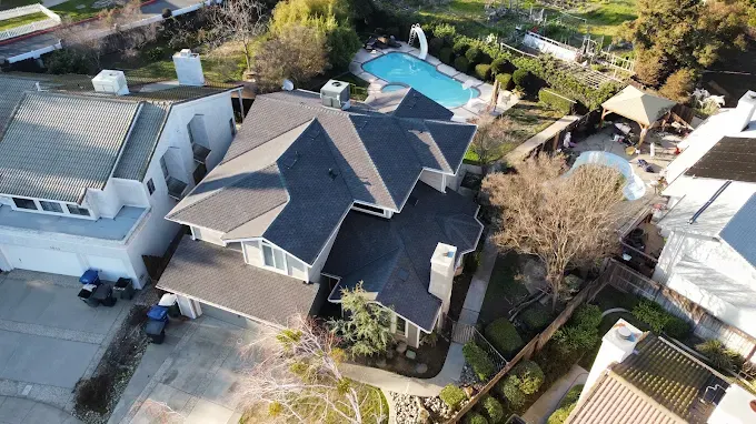 Modern residential home in Modesto with detailed asphalt shingle roof, lush landscaping, and clear suburban background