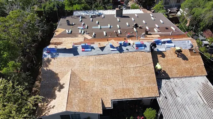 Freshly completed flat roof installation on modern commercial building in Modesto CA with lush landscaping and clear sky