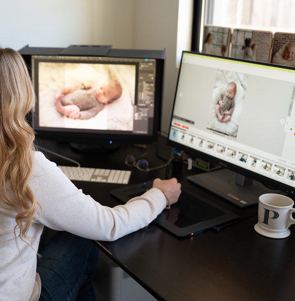 Newborn photographer working on a photo editing workflow at a desk and laptop