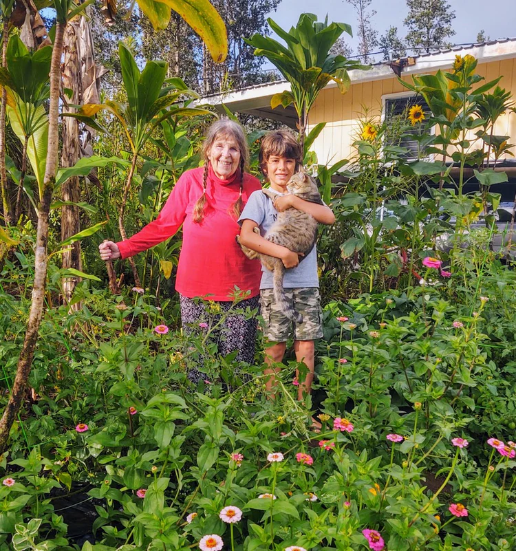Joy Johnson practicing prayer beside ti plants, symbolizing respect and spiritual connection.