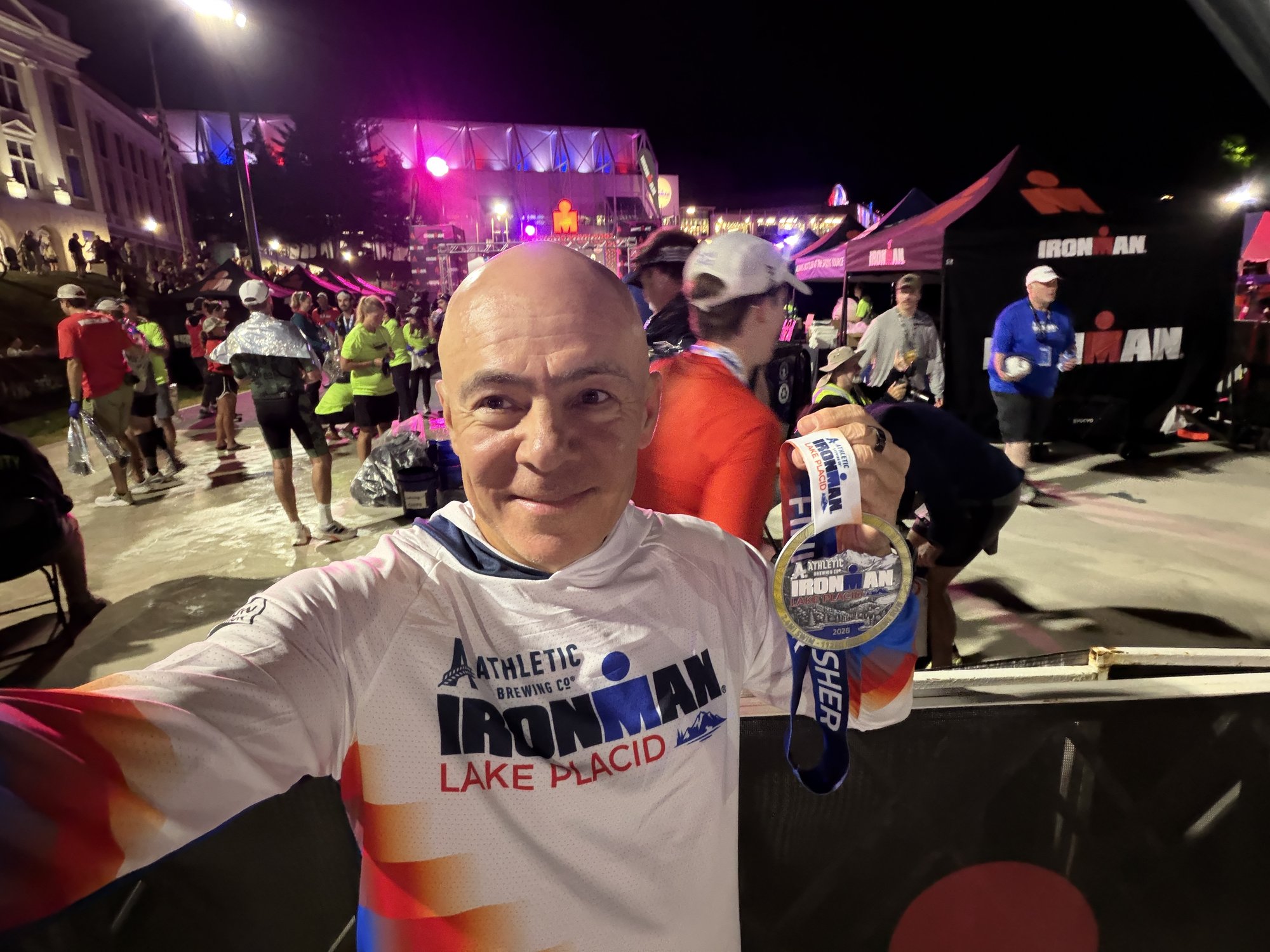 Igor holding his Ironman Lake Placid 2026 finisher medal.
