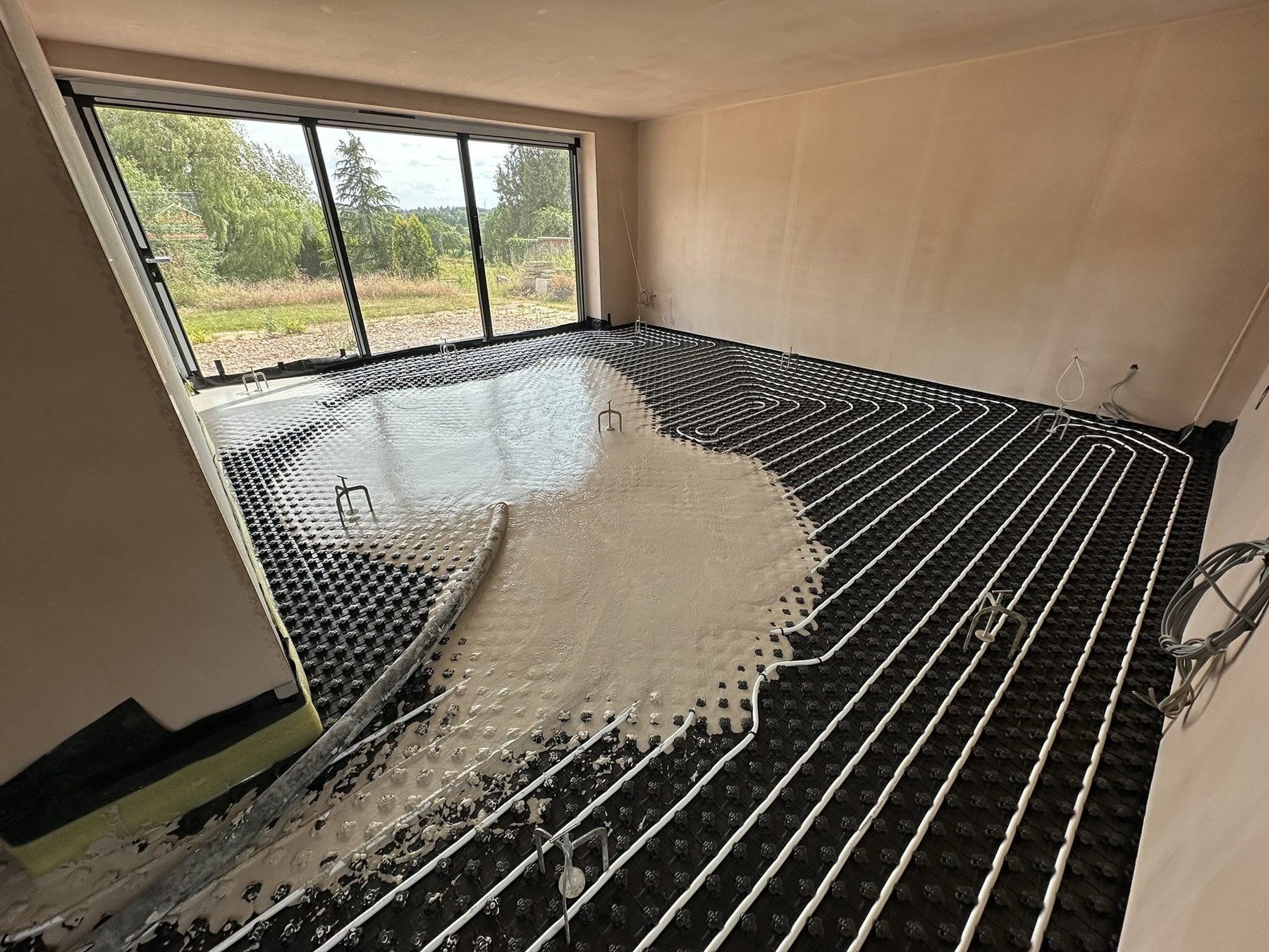 Liquid screed being poured over underfloor heating at the Solihull Road renovation