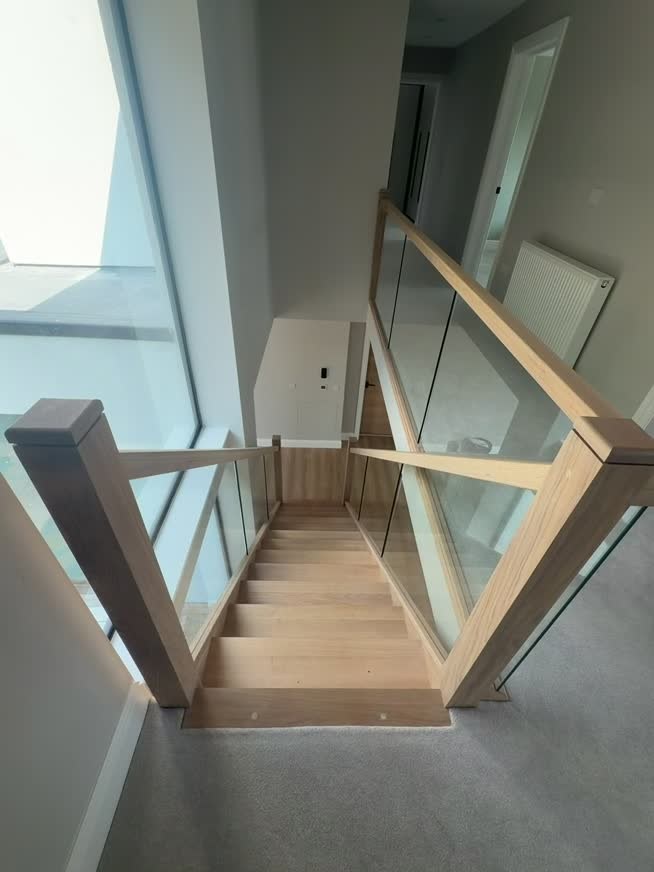 Oak and glass staircase viewed from the upper landing at Solihull Road