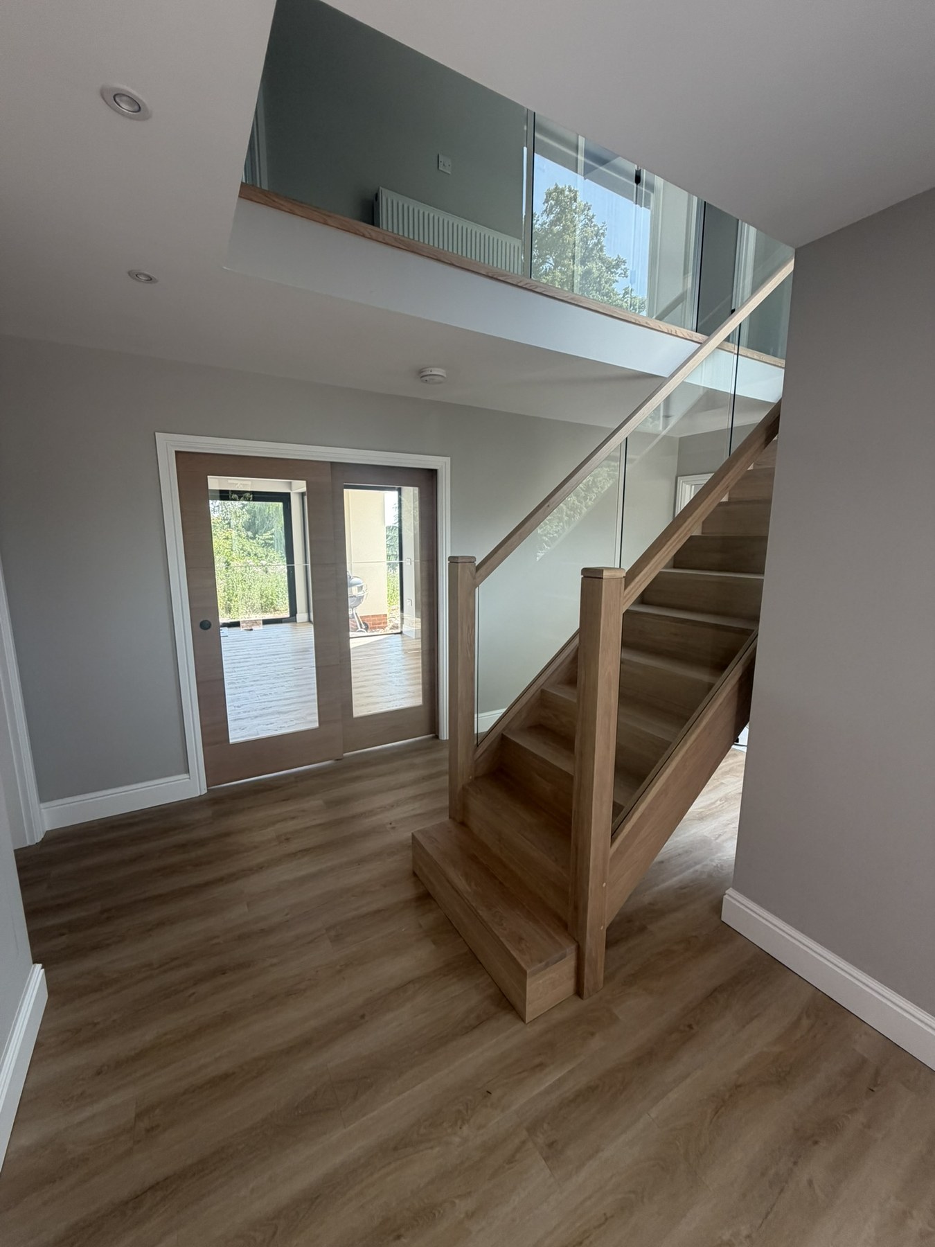 Completed oak staircase with glass balustrade and glazed double doors at Solihull Road