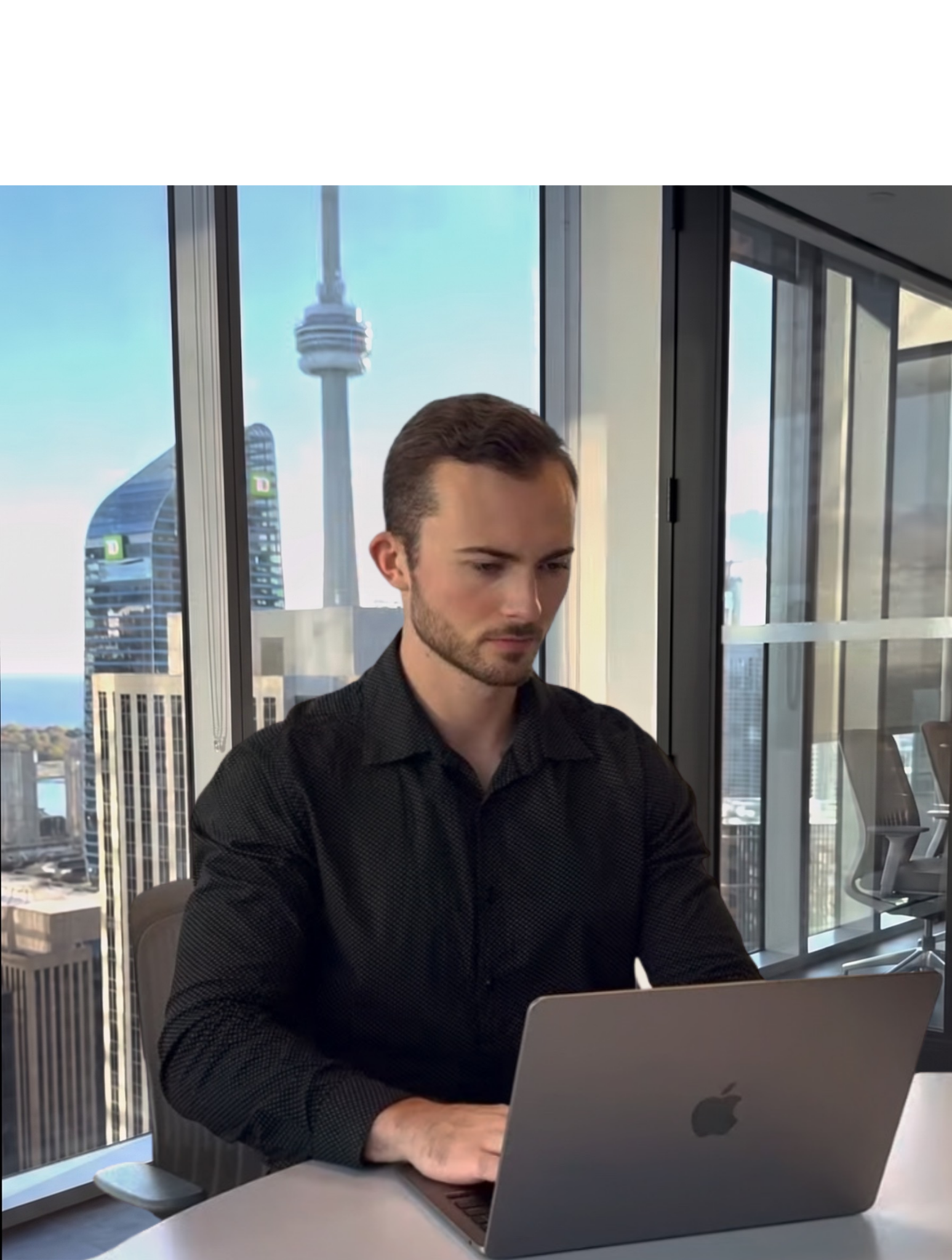 Jordan working at a laptop with the Toronto skyline behind him