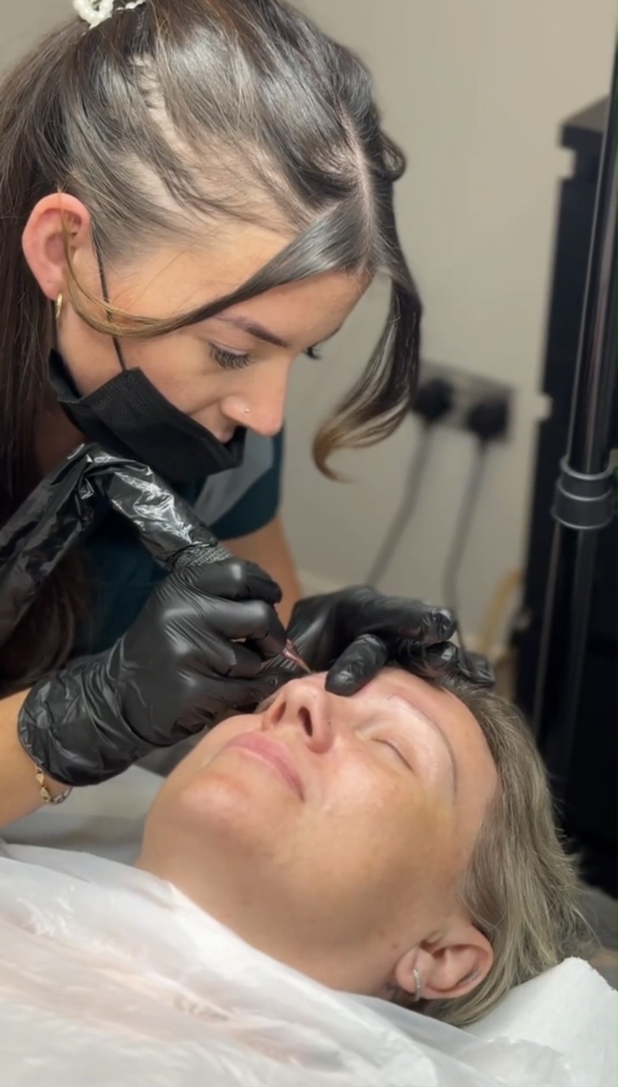 A practitioner carefully carrying out a permanent eyebrow makeup treatment