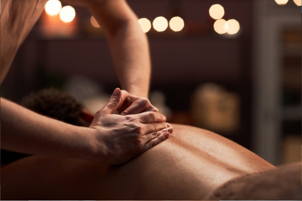 Swedish massage with long flowing strokes in warm candlelight