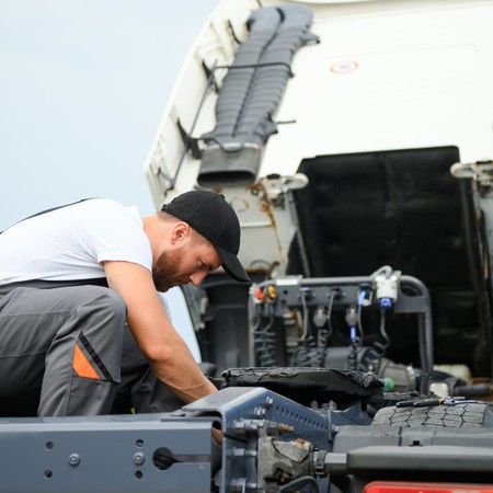 Mobile diesel technician repairing commercial truck on-site