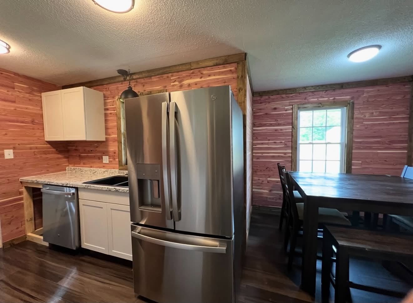 Finished kitchen with white cabinetry, stainless steel appliances, and a dining area