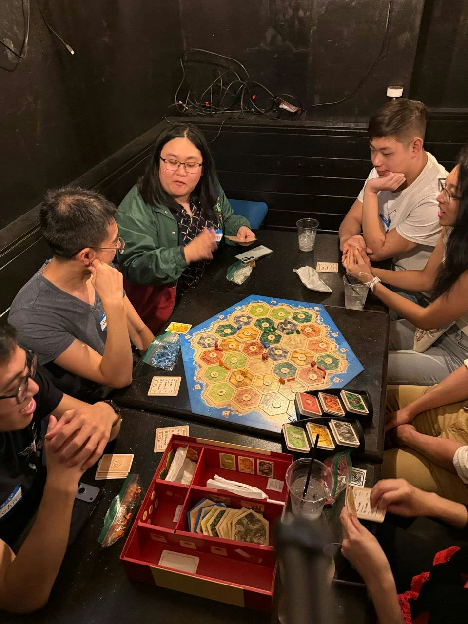 Players gathered around a board game, talking through the next turn