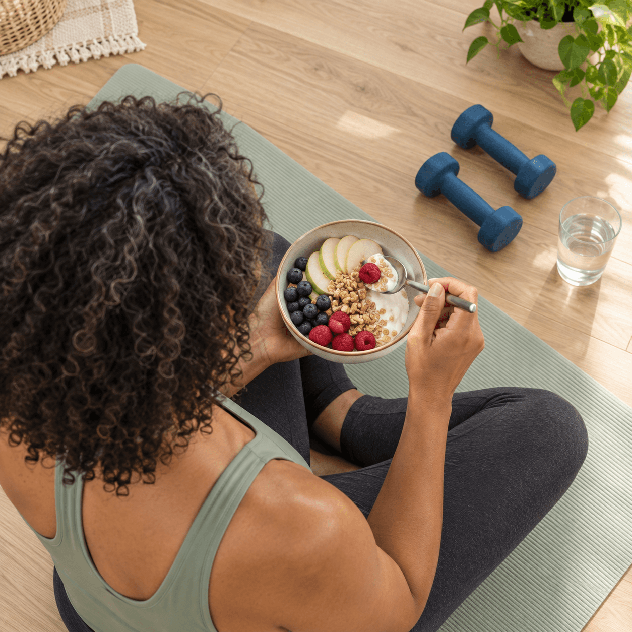 Woman eating a healthy meal beside exercise equipment as part of a medically guided weight management plan.